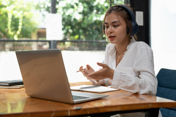 Інтернет-освіта, електронне навчання. молода жінка вивчає дистанційно, використовує ноутбук, слухає онлайн-лекцію, робить нотатки, сидячи вдома
 - Фото, зображення