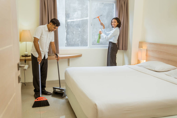 two cleaning staff working cleaning the room with cleaning equipment in the hotel room - Φωτογραφία, εικόνα