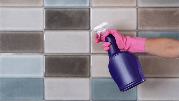 Kobieta w gumowych rękawiczkach myje płytki w kuchni lub łazience gąbką i spryskuje detergentem - Zdjęcie, obraz