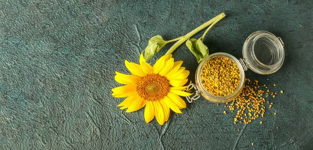 Jar of healthy bee pollen and sunflower on dark background with space for text - Foto, imagen