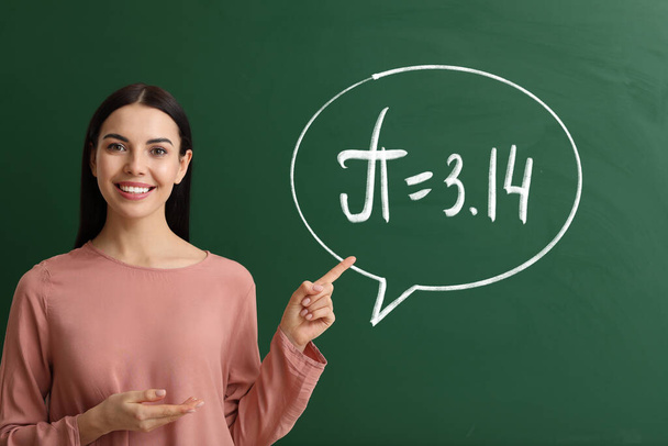 Female teacher near blackboard with written number Pi  - 写真・画像