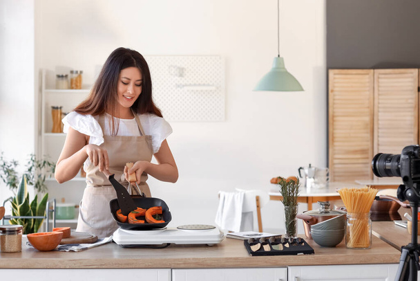 Young Asian woman frying pumpkin while recording video class in kitchen - Photo, image