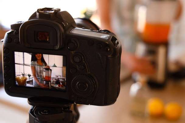 Молода жінка використовує блендер на дисплеї фотоапарата на кухні, крупним планом
 - Фото, зображення