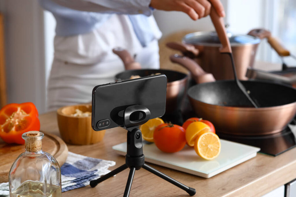 Stand with mobile phone on table in kitchen, closeup - Photo, Image