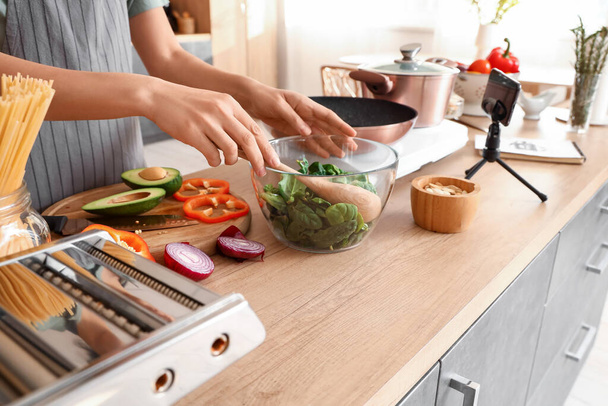 Young woman making salad while following video tutorial in kitchen, closeup - Photo, image