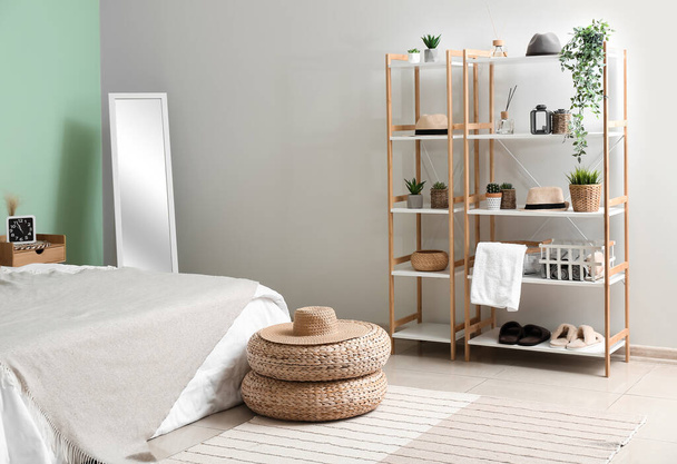 Interior of cozy bedroom with rattan poufs, mirror and shelving unit - Fotoğraf, Görsel