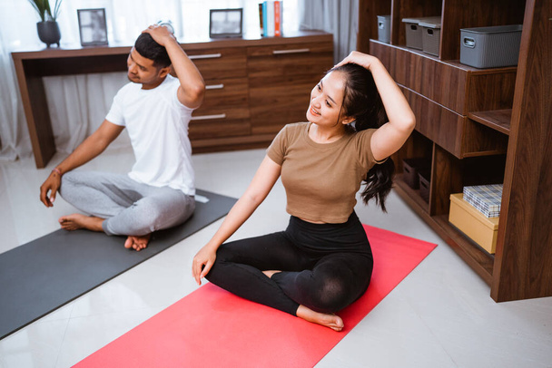 portrait of young asian couple workout together at home stretching their body - Φωτογραφία, εικόνα