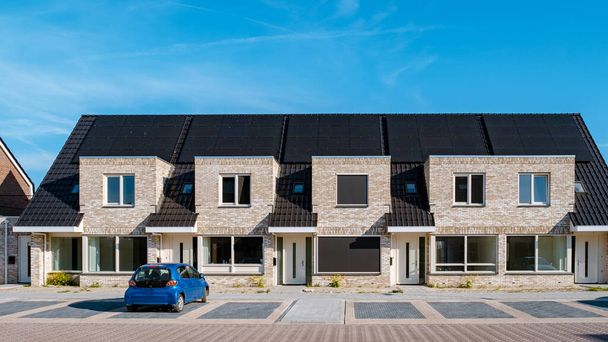 Newly build houses with solar panels attached on the roof against a sunny sky Close up of a new building with black solar panels. Zonnepanelen, Zonne energie, Translation: Solar panel, , Sun Energy.  - Fotografie, Obrázek