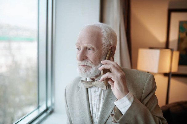 Important call. Senior businessman talking on the phone and looking serious - 写真・画像
