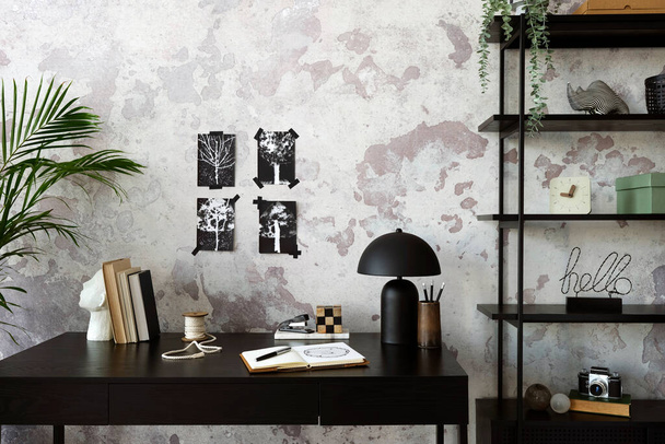 Concrete interior of home office with black desk,  lamp, image, office accessories and plants. Rack with personal accessories. Home decor. Template.  - Foto, Imagen