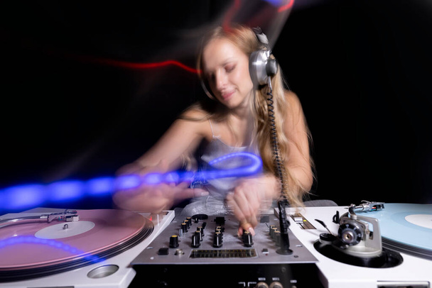 Beautiful female dj playing with turntables and overlayed light trails - Photo, image