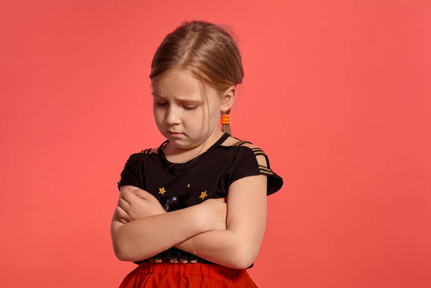 Close-up shot of a fine blonde little girl in a combined dress, looking offended while posing against a pink background with copy space. Concept of a happy childhood. - Foto, Bild