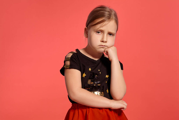 Close-up shot of a pretty blonde little female in a combined dress, looking disappointed while posing against a pink background with copy space. Concept of a happy childhood. - Zdjęcie, obraz