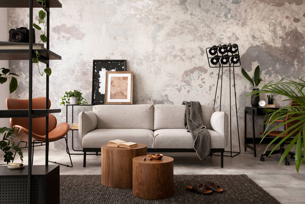 The stylish compostion at concrete living room interior with design gray sofa, wooden coffee table, desk and elegant personal accessories. Loft and industrial interior. Home decor. Template. - Foto, afbeelding