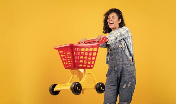 happy woman carry shopping cart. shopper girl have fun. marketing concept. Female housewife with shopping trolley in supermarket. girl pushing shopping cart in the mall. - Zdjęcie, obraz