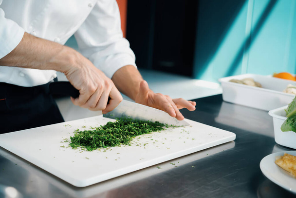 Close-up of a chef finely chopping herbs in a professional kitchen - Zdjęcie, obraz