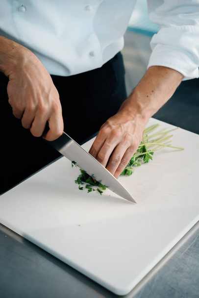Close-up of a chef finely chopping herbs in a professional kitchen - Φωτογραφία, εικόνα