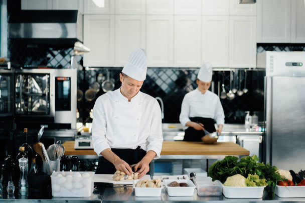 Professional kitchen: two chefs prepare delicious dish in a restaurant - 写真・画像