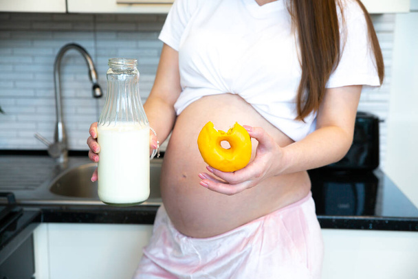 Pregnant woman holding Bottle of milk and Sweet donut. Healthy food during pregnancy. - Fotografie, Obrázek
