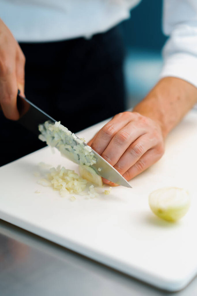 Close-up: the chef cuts the onion finely in professional kitchen of the restaurant - 写真・画像
