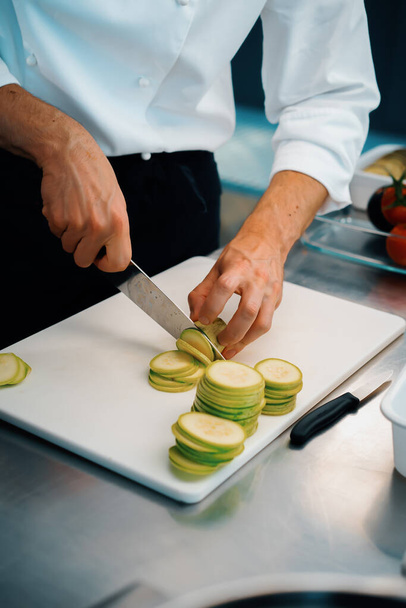 Close-up of chef slicing zucchini in a professional restaurant kitchen - Foto, Imagem