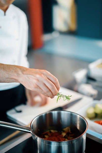 Professional restaurant kitchen, close-up: the chef throws greens into pan - Valokuva, kuva