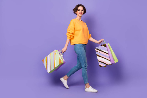 Full length body size view of attractive cheerful girl going with bags retail eshop delivery isolated over violet lilac color background. - Fotoğraf, Görsel