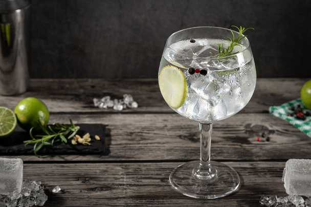 Cold glass of gin tonic with ice on dark rustic background . - 写真・画像