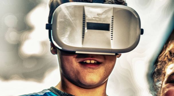 Happy face of a young boy using VR glasses. Virtual reality experience. - Foto, Imagen