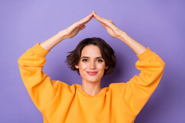 Portrait of attractive cheerful girl holding roof over head safe place isolated over violet lilac color background. - Φωτογραφία, εικόνα