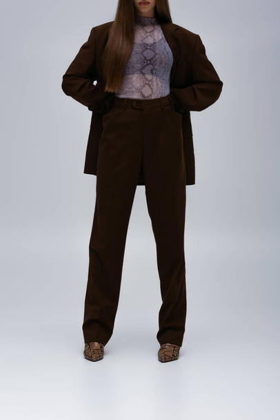 cropped view of teenage model in brown high-quality suit posing on grey - Foto, Imagem