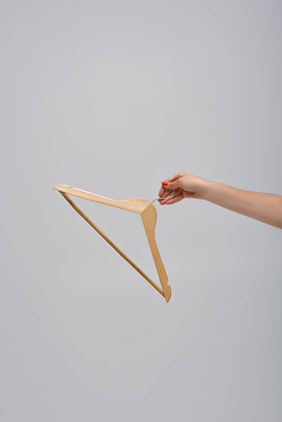 cropped view of woman holding wooden hanger isolated on grey - Foto, immagini