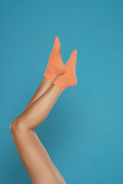 Pretty female legs in orange short socks, on a blue background. - Foto, Imagen