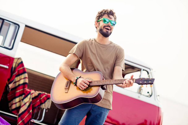 Portrait of overjoyed cheerful handsome guy enjoy playing acoustic guitar have good mood outdoors. - Photo, image