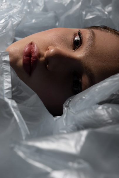 close up of model lying around plastic bags, recycle fashion concept - Foto, immagini