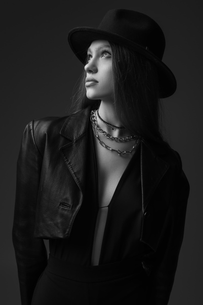 monochrome photo of teenage model in fedora hat posing in studio  - Foto, imagen