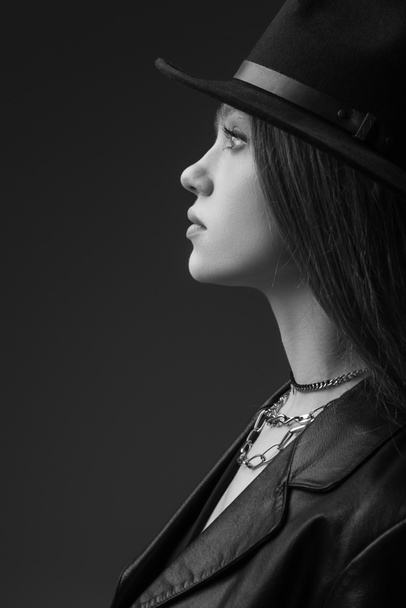profile of teenage model in fedora hat posing in studio, monochrome photo - Foto, immagini