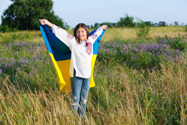 Happy girl with national flag of Ukraine in field. Space for text - Foto, imagen
