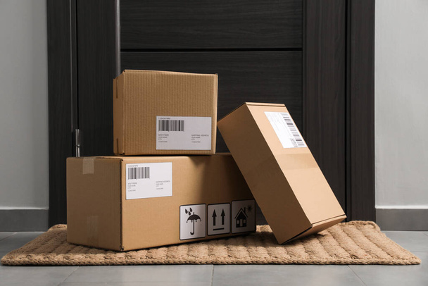 Cardboard boxes on floor mat near entrance. Parcel delivery service - Photo, image