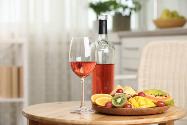 Delicious exotic fruits and wine on wooden table indoors - Foto, Imagem