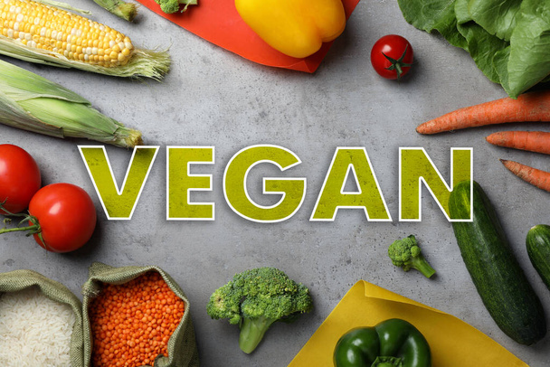 Word Vegan and fresh products on light grey background, flat lay - Fotó, kép