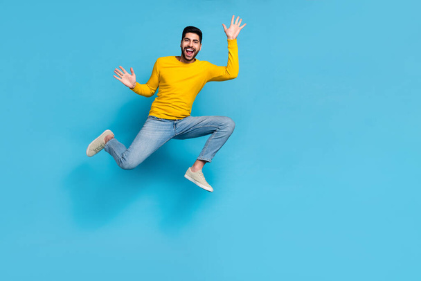 Full length photo of sportive energetic person jumping raise hands empty space isolated on blue color background. - Foto, Imagen