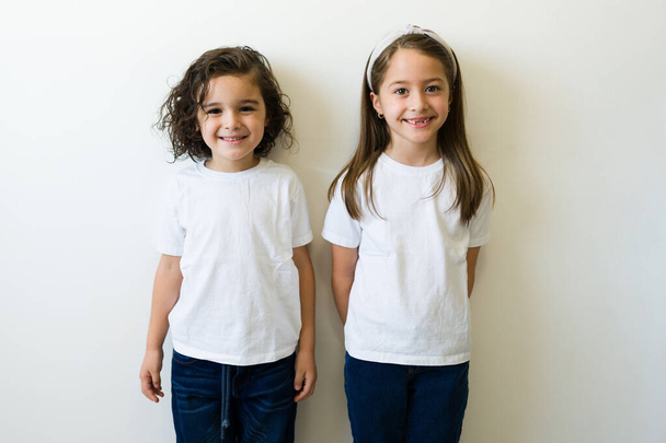 Cute girl and boy wearing white shirts. Front and rear view of a mock up t-shirt for design print or logo for kids - Valokuva, kuva