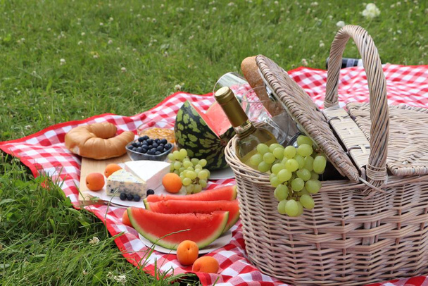 Picnic blanket with delicious food and wine outdoors on summer day - Φωτογραφία, εικόνα