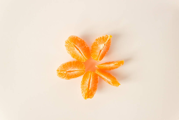 Zralé oloupané mandarinky, plátky mandarinek leží v kruhu, izolované na bílém pozadí. Tradiční zimní vánoční ovoce. Koncept ovocné a syrové stravy. - Fotografie, Obrázek