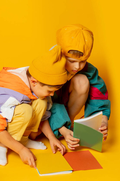 Дві дитини в стильному вінтажному 80-х одязі розважаються на жовтому тлі
 - Фото, зображення