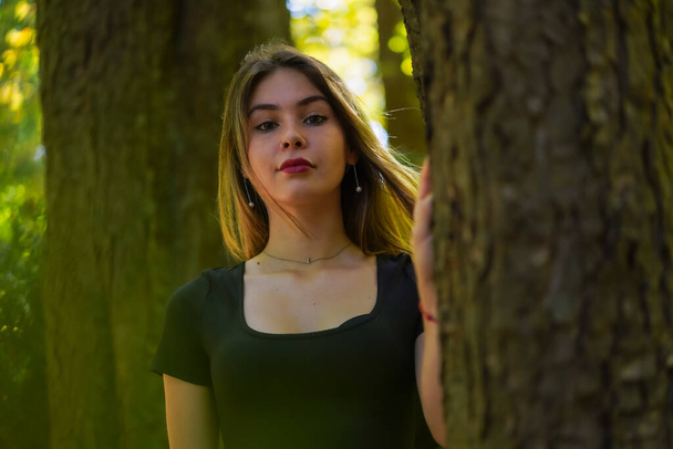 Portrait of a young woman next to a tree in nature in a natural park - Foto, Imagen