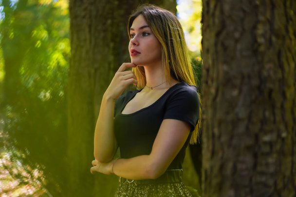 Posing of a young woman next to a tree in nature in a natural park - Photo, Image