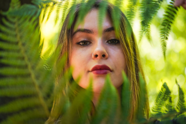 Portrait of a young woman in nature in a natural park with some fern leaves - Fotoğraf, Görsel