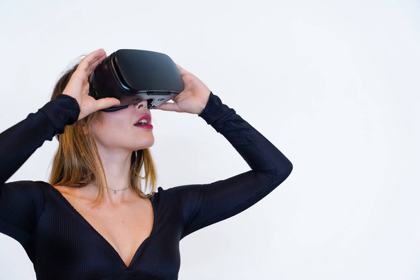 Woman wearing virtual reality goggles on white background, futuristic concept, metaverse, smiling - Fotó, kép